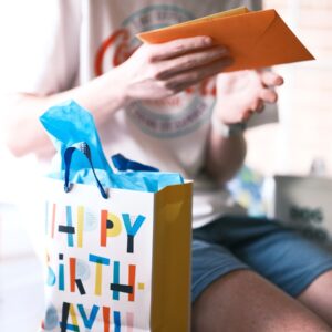 a person sitting on a table with a birthday bag